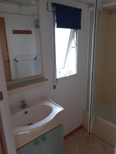 une salle de bain avec un lavabo, un miroir et une fenêtre dans l'établissement Mobil Home bord de mer CAMPING LES TAMARIS, à Saint-Pierre-dʼOléron