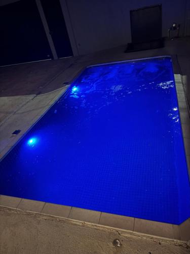 a blue swimming pool with lights on the floor at Maggi Residence in Batatais