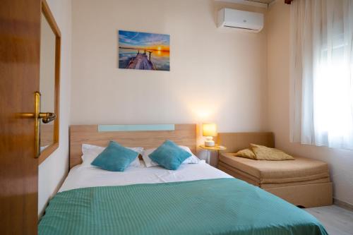 ein Schlafzimmer mit einem Bett mit blauen Kissen und einem Stuhl in der Unterkunft Villa МareMaria in Nea Kallikratia