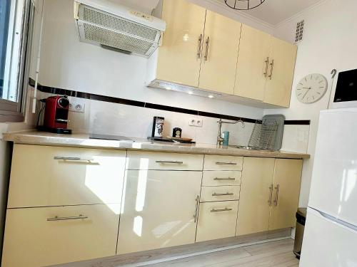 une cuisine avec des placards blancs et une horloge murale dans l'établissement Charmant 2 pièces Centre cannes proche palais, à Cannes