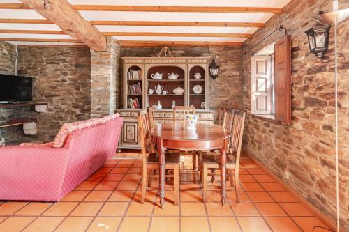 a dining room with a wooden table and a pink couch at Casa da Joana in Mirandela