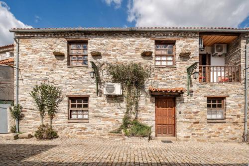 a stone house with a wooden door and windows at Casa da Joana in Mirandela