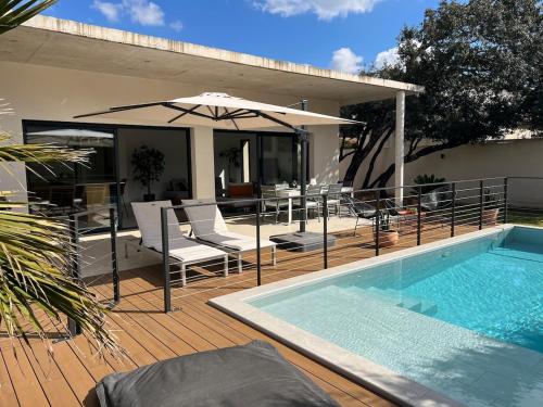 une terrasse avec une piscine et un parasol dans l'établissement Villa moderne avec piscine chauffée, à Villeneuve-lès-Avignon