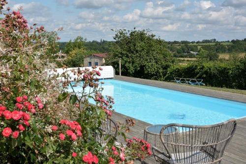 - une piscine avec 2 chaises et des fleurs dans l'établissement Le Rocher classé trois étoiles, N1, à Verruyes