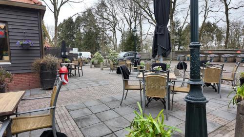 an outdoor patio with tables and chairs and an umbrella at Chalet Kokomo - Gelegen In bosrijkgebied van Drenthe in Eext