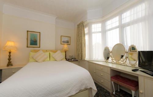 a bedroom with a bed and a tv and mirrors at Shoreline Accommodation in Bournemouth