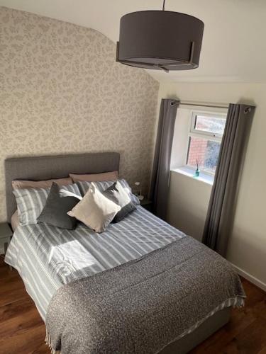 a bedroom with a bed with pillows and a window at Night Owl Cottage in Rainford