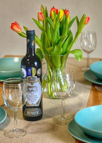 a bottle of wine and glasses on a table with flowers at Apartmány Křivoklát in Křivoklát