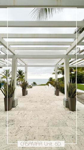 a white pavilion with potted plants on a beach at Escapada Exclusiva en Casamar, playa surf y golf in San Carlos