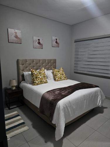 a bedroom with a large bed with yellow pillows at Zeeluli Mbabane CBD Apartments in Mbabane