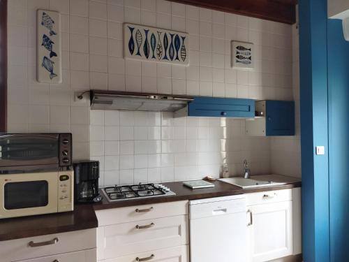 une cuisine avec un micro-ondes et une cuisinière four supérieur dans l'établissement Maison de vacances, au Guilvinec