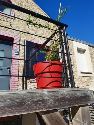 a red pot on a balcony with a plant in it at La maison Kerserho in Plouhinec