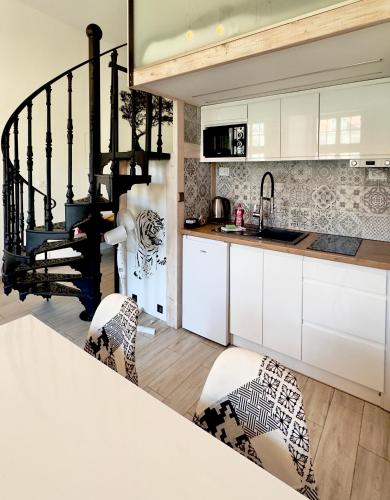 a kitchen with white cabinets and a spiral staircase at Wroclaw Inn Apartments in Wrocław
