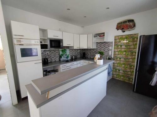 une cuisine avec des armoires blanches et un réfrigérateur noir dans l'établissement La maison blanche et rouge, à Saint-Hélen