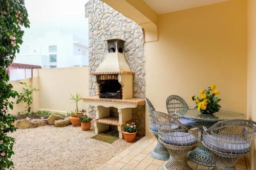 a patio with a fireplace and a table and chairs at Villa Arpeggio - Cozy 3-Bedroom Villa with Private Pool in Montinhos da Luz, Lagos in Mato Porcas
