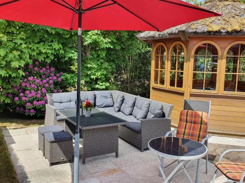 a patio with a couch and a table with an umbrella at Hotel Pension Loose in Borkum