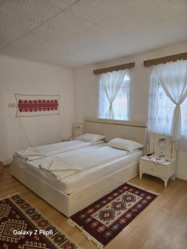Rózsa Panzió في ريميتيا: غرفة نوم بها سرير كبير ونافذتان