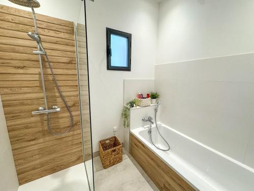 La salle de bains est pourvue d'une baignoire et d'une douche avec une porte en verre. dans l'établissement Villa neuve moderne, à Saint-Quentin-la-Poterie