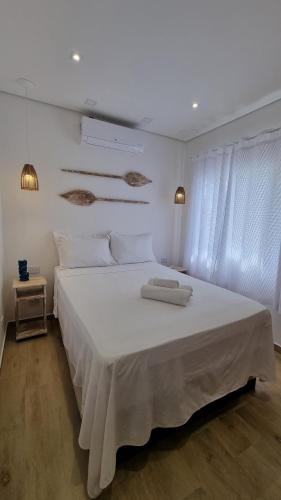 a bedroom with a large white bed with white sheets at Casa da Tieko - Suítes no Perequê in Ilhabela