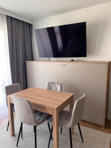 a wooden table with chairs and a television on a wall at Apartamenty Novela Centrum in Słupsk