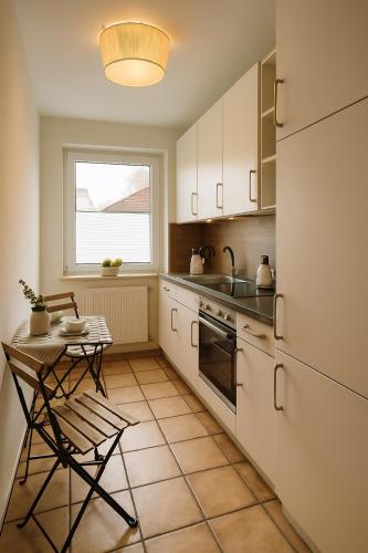 a kitchen with white cabinets and a table and a window at Hotel Schultheiss Hameln in Hameln