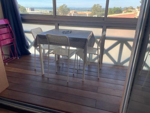 une table et des chaises sur un balcon avec une fenêtre dans l'établissement Studio Sète vue sur l’étang de Thau, à Sète