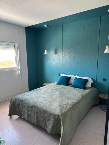 a bedroom with a large bed with blue walls at vue mer in Pataias