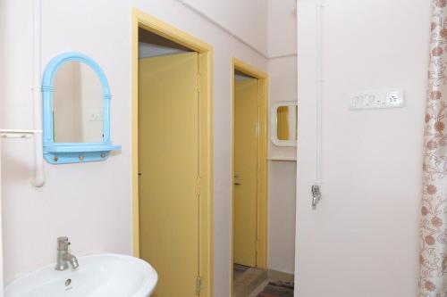 a bathroom with a sink and a yellow door at KHS-Keshav in Ambāsamudram