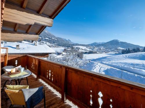 a balcony with a table and chairs and snow covered mountains at Bio-Bauernhof Niederlehen in Fieberbrunn