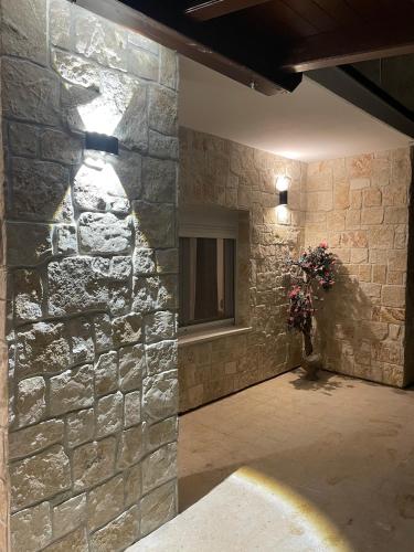 a stone wall with a window and a vase of flowers at Stonehouse-Pag in Povljana