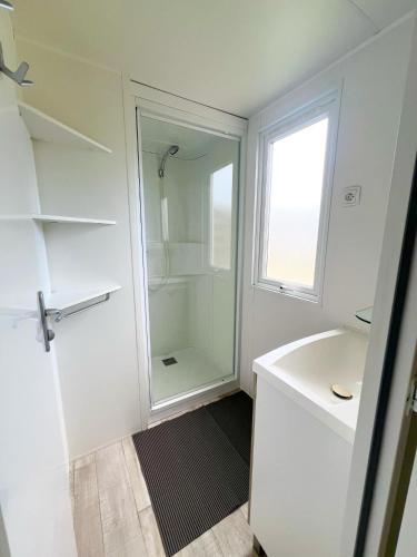 une salle de bain blanche avec une douche et un lavabo dans l'établissement Mobil-home Argelès-sur-Mer, à Argelès-sur-Mer