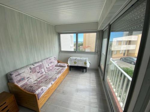 une chambre avec un canapé sur un balcon avec une table dans l'établissement Appartement front de mer port leucate, à Leucate-Plage