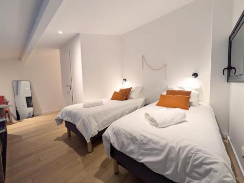 a bedroom with two beds with white sheets and orange pillows at Maison aux portes de Bordeaux et de son vignoble in Villenave-dʼOrnon