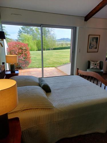 un grand lit dans une chambre avec une grande fenêtre dans l'établissement Maison 3 chambres avec piscine, à Dolmayrac