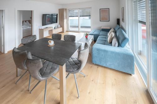 a living room with a table and a blue couch at Amaria Downtown Aparthotel Villach in Villach