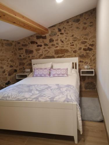 a white bed in a room with a stone wall at O Muiño do Torneiro in A Pobra do Caramiñal