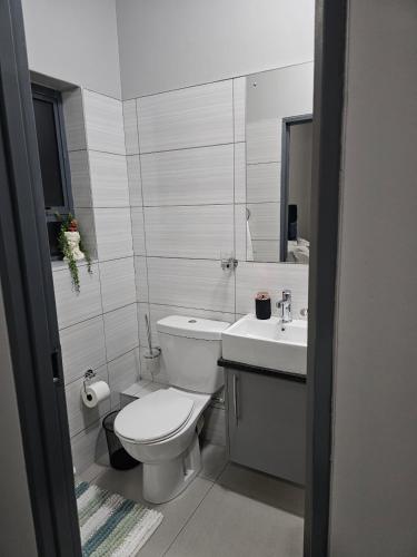 a white bathroom with a toilet and a sink at Zeeluli Mbabane CBD Apartments in Mbabane