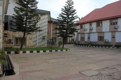 a courtyard with two buildings and two trees at Adbates Suites and Recreation in Oshogbo