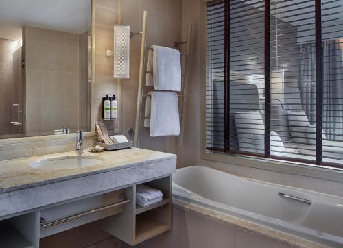 a bathroom with a sink and a bath tub at Pullman Phuket Panwa Beach Resort in Panwa Beach
