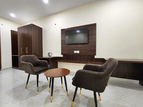 a room with two chairs and a table and a tv at Raina's BnB in Solan