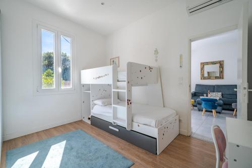 Cette chambre blanche dispose de lits superposés et d'un canapé. dans l'établissement Cosy 4 pièces clim Terrasse Jacuzzi, à Nice