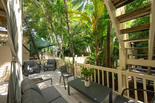 a porch with chairs and tables and trees at Heron Hideaway in Key West