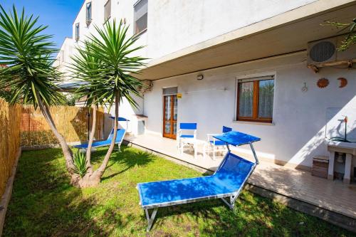 a yard with blue chairs and a table and a palm tree at La casa di Marcello in Orbetello