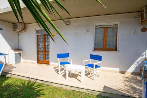 a patio with blue chairs and a table and a house at La casa di Marcello in Orbetello