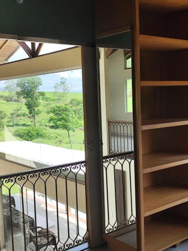 a room with a balcony with a view of a yard at Sitio Vagalumes em Engenheiro Passos RJ próximo a Penedo in Resende