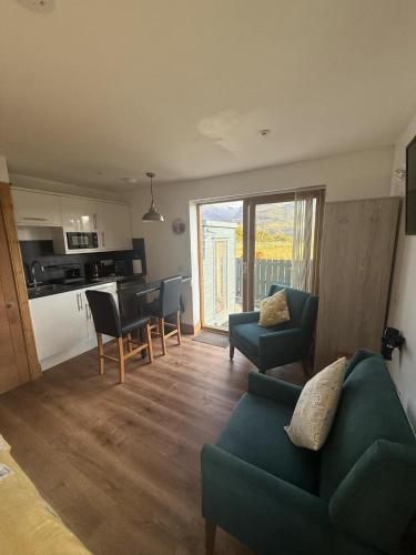 a living room with a green couch and a kitchen at Ben Nevis Manor Studio with private Hot Tub in Fort William