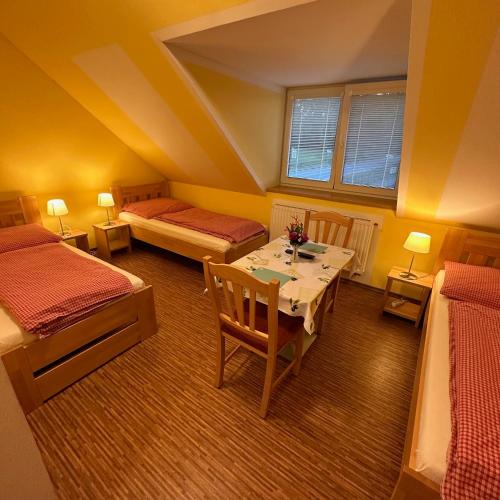a room with two beds and a table and chairs at Pension Mijami in Dolní Bukovsko