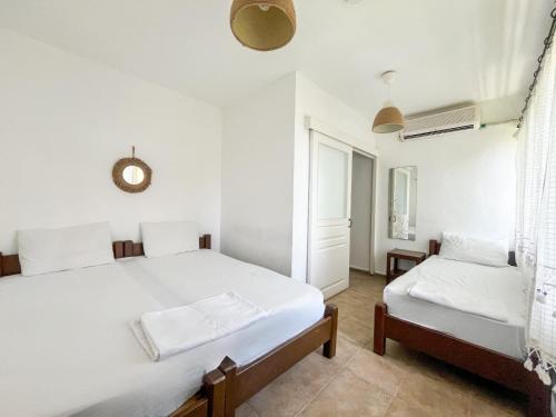 a white bedroom with two beds and a window at Esen Apartments in Ula