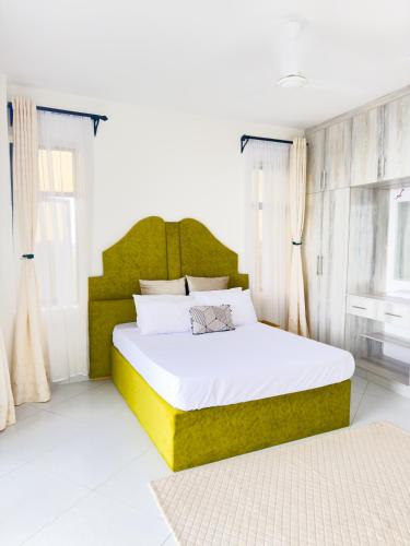 a bedroom with a large bed with a green headboard at Marina Beachfront at JUMEIRAH PALM RESORT-NYALI in Mombasa