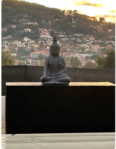 une statue d'une femme assise sur un banc avec une ville dans l'établissement Suite parentale, au Beausset